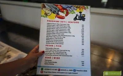 Menu z owocami morza i rybami, część albańskiej kuchni. Widoczne kalmary, krewetki, ośmiornice, ryby i wina.