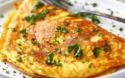 En gyllene omelett, perfekt för ett snabbt omelett recept. Garnerad med färsk persilja och serverad på en vit tallrik med en gaffel.
