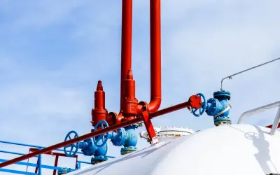 Zawory i rury na białym zbiorniku na gaz. Zastanawiasz się, na ile wystarcza zbiornik na gaz 2700?
