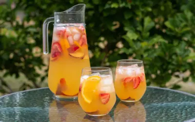 En karaff och två glas med en uppfriskande cava drink fylld med is, jordgubbar och apelsinskivor. Perfekt för en sommardag.