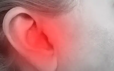Czerwony rumień na uchu, obejmujący helix, sugeruje ból lub stan zapalny.