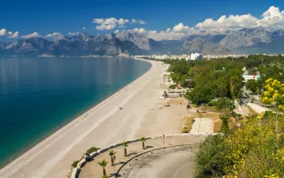 Piękna plaża i turkusowe morze w Turcji, idealne miejsce na wakacje. W tle góry i miasto.