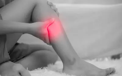 Donna che si tiene la gamba, evidenziata in rosso, a causa di dolori alle gambe, un possibile problema neurologico.