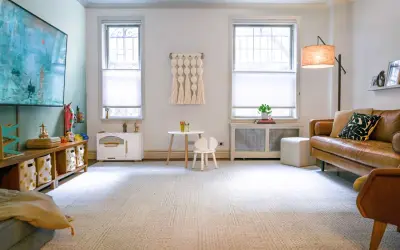 A cozy DIY play room with a brown leather sofa, a small table and chair, and toy storage.