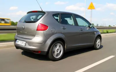 Szary Seat Altea 1.9 TDI w ruchu drogowym, z widocznym znakiem ostrzegawczym.