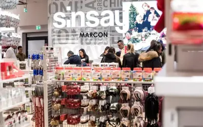 W Sinsay można płacić Blikiem. W sklepie Sinsay klienci robią zakupy, a na półkach widać akcesoria i drobne zabawki.