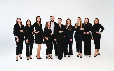 Grupa profesjonalistów w czarnych garniturach pozuje na białym tle.