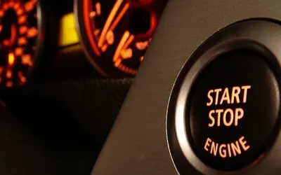 Bouton "START STOP ENGINE" illuminé, prêt à démarrer ou arrêter le moteur. Les cadrans du tableau de bord brillent en orange.