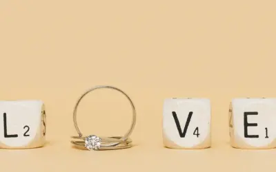 Un anillo inicial de oro con un diamante, junto a cubos que forman la palabra "LOVE".