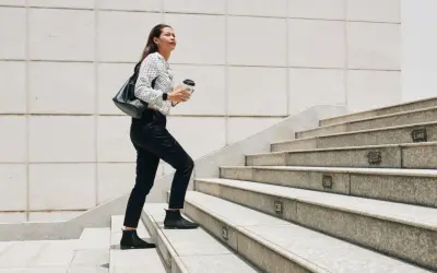Frau steigt Treppen hoch, Kaffee in der Hand. Ein guter Weg, um abzunehmen durch gehen und fit zu bleiben.