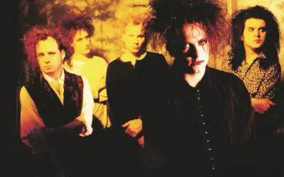 Zespół The Cure w charakterystycznych fryzurach i makijażu. Ich mroczne utwory niosą emocje.