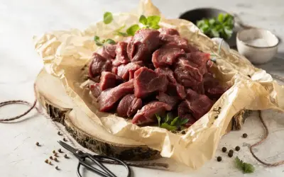 Pokrojone w kostkę mięso na gulasz z dzika, ułożone na papierze, gotowe do przyrządzenia.