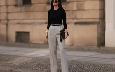 Eleganckie stylizacje dla 40 latki: czarny dopasowany golf, szare szerokie spodnie, czarny pasek i kopertówka. Klasa i szyk.
