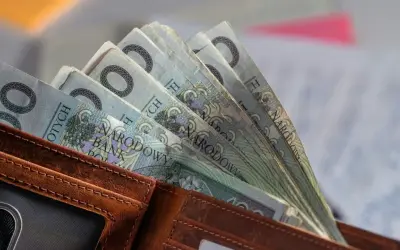 Portfel z polskimi banknotami 100 zł. W tle dokumenty, być może związane ze świadczeniem pielęgnacyjnym 2026.