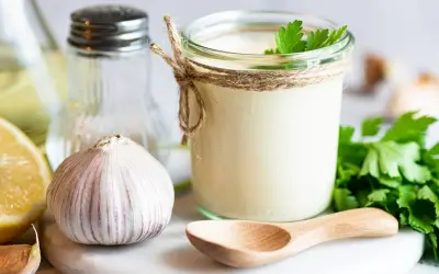Sos aioli w słoiku, czosnek, cytryna i zioła. Różnica między sosem aioli a klasycznym majonezem czosnkowym jest subtelna, ale wyczuwalna.
