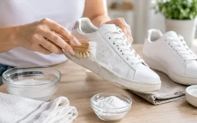 Mani che puliscono scarpe bianche con una spazzola, mostrando come lavare le scarpe con bicarbonato e sapone.