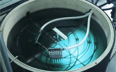 Ein großer Tank mit Wasser, Rohren und einem Gerät zur Eisbildung. Hier wird ein **Eisspeicher selber bauen**-Projekt umgesetzt.
