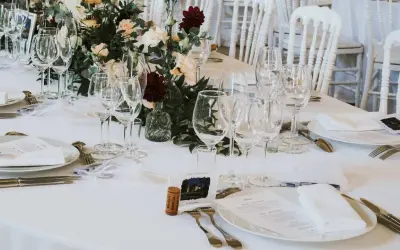 Un élégant dressage d'une table à la française, prêt pour un festin. Verrerie étincelante, fleurs fraîches et menus attendent les convives.