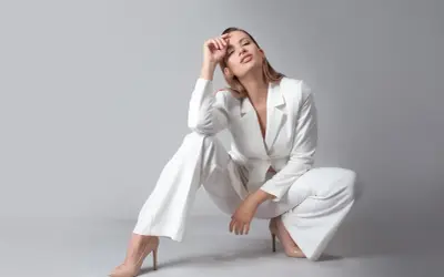 Elegancka kobieta w białym garniturze i cielistych szpilkach. Idealne buty do białego garnituru podkreślają stylizację.