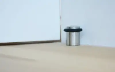 Elegancki, metalowy odbojnik z czarną gumką chroni ścianę przed uderzeniem drzwi.