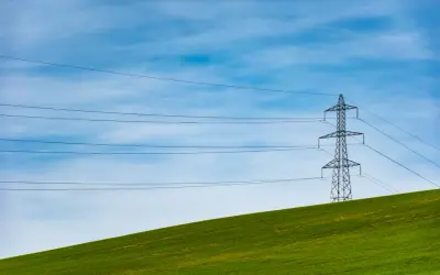 Słupy energetyczne na zielonym wzgórzu, symbolizujące zmianę dostawcy prądu i nowoczesność.