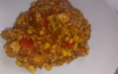 Pyszne kaszotto z kurczakiem, kukurydzą i pomidorami na białym talerzu.