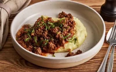 Herzhaftes Hackfleisch mit Tomatensauce auf cremigem Kartoffelpüree, garniert mit Petersilie. Ein einfaches und leckeres Haschee Rezept.