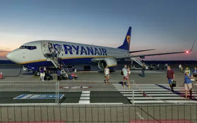 Ryanair przyloty Modlin: pasażerowie schodzą po schodkach z samolotu na płycie lotniska o zmierzchu.