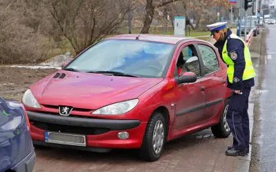 Policjantka kontroluje czerwony samochód. Czy można jeździć bez plastiku po zdaniu egzaminu?