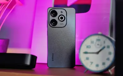 Szary smartfon Infinix z potrójnym aparatem na tle różowego światła. Czy to Infinix co to za firma?