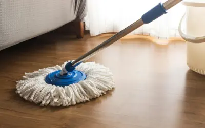 Mop z mikrofibry na drewnianej podłodze, gotowy do czyszczenia. Dowiedz się, czym nabłyszczyć panele, by lśniły jak nowe.