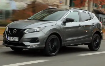 Szary Nissan Qashqai 2019 z czarnymi felgami pędzi ulicą, otoczony jesienną scenerią.