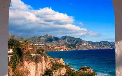 Vue panoramique de la côte andalouse, parfaite pour un guide Malaga. Falaises rocheuses, mer bleue et montagnes verdoyantes sous un ciel d'azur.