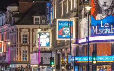 Tętniący życiem west end nocą, z neonami teatrów Apollo, Gielgud i plakatami "Les Misérables" oraz "The Crucible".