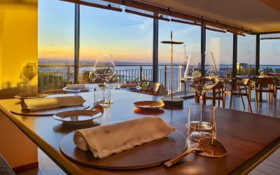 Tavola apparecchiata in un ristorante stellato a Gabicce Monte, con vista sul tramonto sul mare.