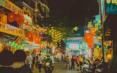 Tętniąca życiem nocą ulica w Ho Chi Minh (miasto), ozdobiona flagami Wietnamu i lampionami.