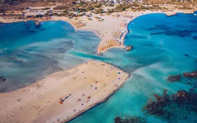 Rajska, piaszczysta kreta plaża Elafonisi z turkusową wodą i licznymi parasolami.