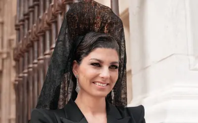 Mujer con peinado boda gitana, velo de encaje negro y pendientes largos. Sonríe con elegancia.