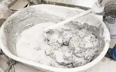 Mieszanie wapna gaszonego w dużej kadzi, tworząc gładką masę do prac budowlanych.