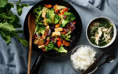 Wok z warzywami i tofu, miseczka ryżu i zupy.