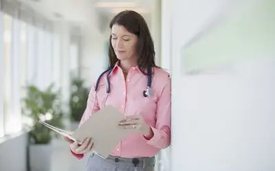 Médecin consultant un dossier, peut-être pour un deuxième avis médical et son remboursement.