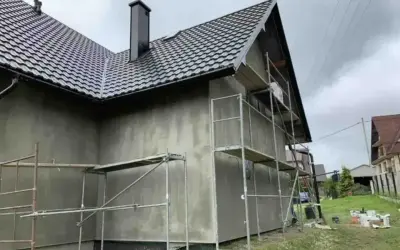 Dom w trakcie prac elewacyjnych, rusztowania wokół, szara ściana. Sprawdzamy elewacja cena za m2 robocizna.