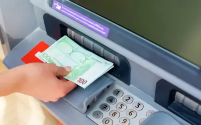 Ręka odbiera banknoty 100 euro z bankomatu PKO.