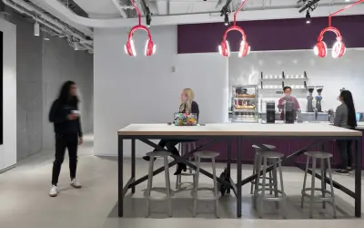 Inside Spotify Studios NYC, people gather around a communal table, with iconic headphone lights overhead.
