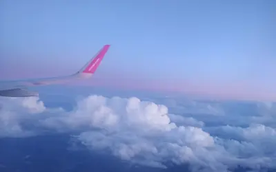 Skrzydło samolotu Wizz Air nad chmurami, wczesny poranek. Czas na loty do Anglii!
