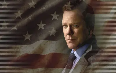Kiefer Sutherland jako Tom Kirkman w serialu "Designated Survivor". Obsada serialu w tle z amerykańską flagą.