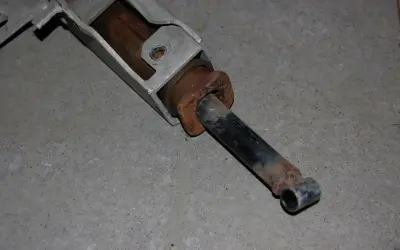 En rostig stötdämpare, troligen en påskjutsreserv kort, ligger på betonggolv.