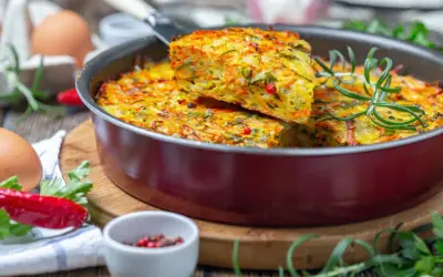 Pyszna, warzywna zapiekanka z jajek i warzyw, idealna na lekka kolacja. Podana z gałązką rozmarynu i papryczką chili.