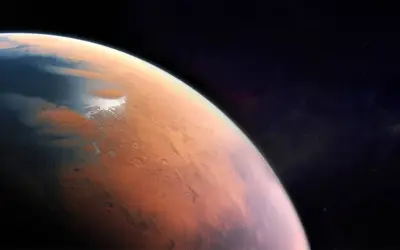 Widok Marsa z kosmosu. Czerwona planeta z lodowymi czapami i kraterami. Jaka temperatura jest na Marsie? Niska, średnio -63°C.