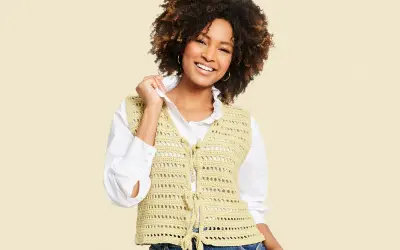 Mujer sonriente con chaleco de crochet con patrón calado, atado al frente.